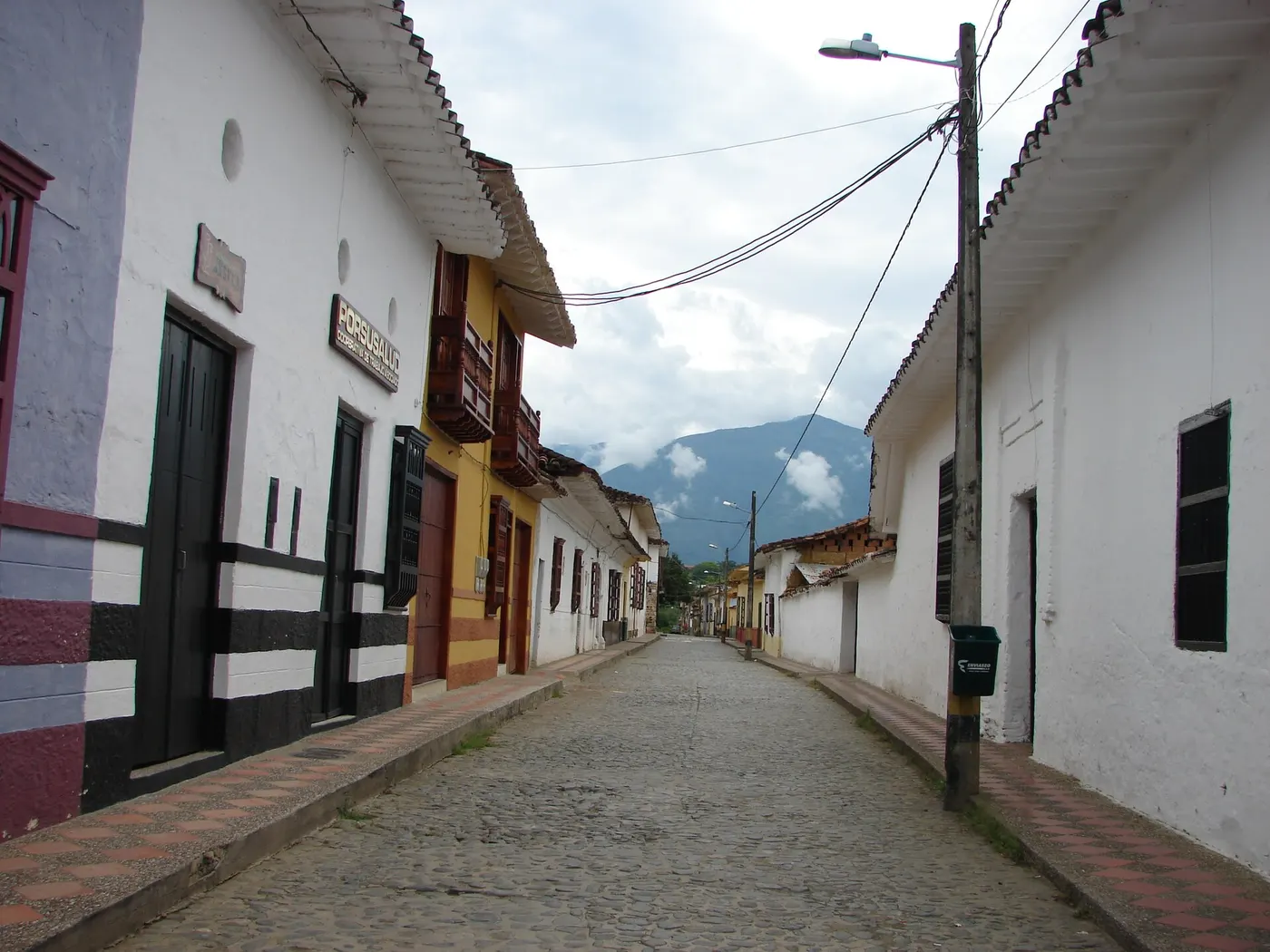 Calle empedrada con casas encaladas y montañas al fondo