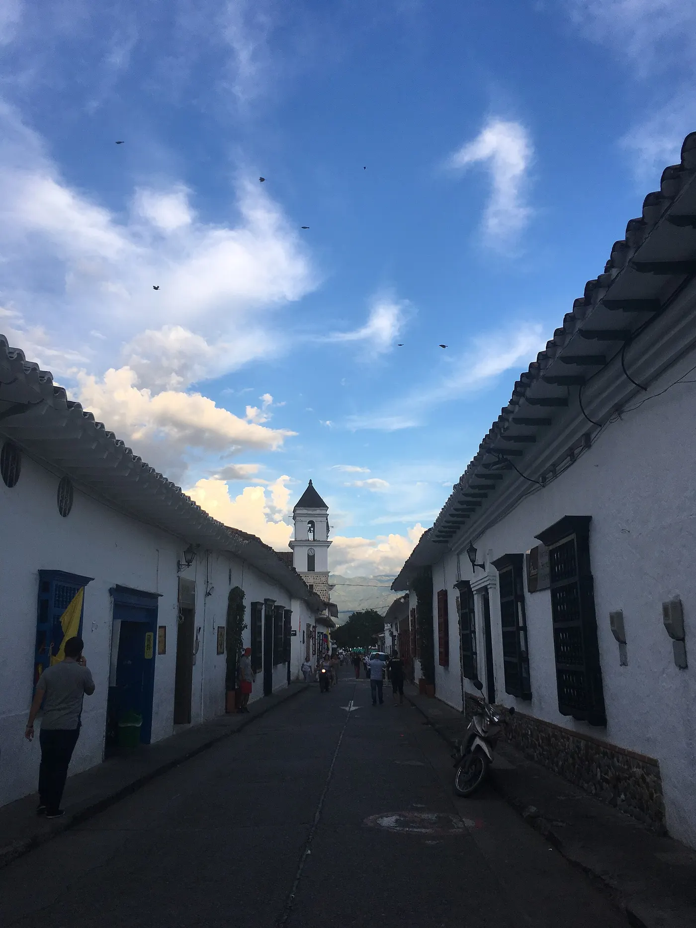 Calle típica con casas blancas, puertas de madera y montañas al fondo