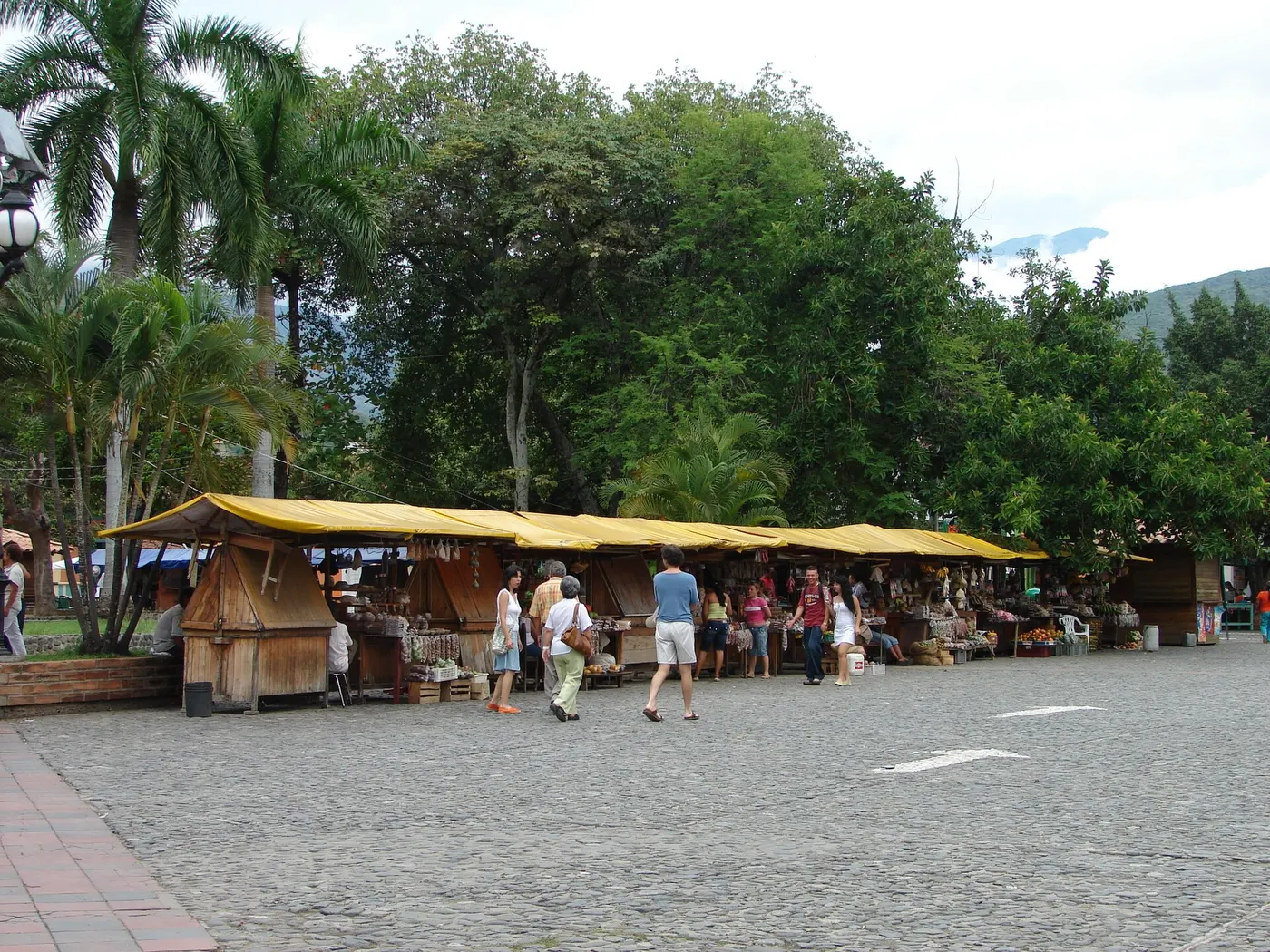 Toldos de dulces y frutas bajo las palmas de la plaza